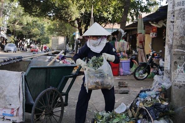 Chị Trần Thị Tuyết, nhân viên Xí nghiệp Vệ sinh đang thu gom rác trên đường Mạc Thị Bưởi (TP. Buôn Ma Thuột). 