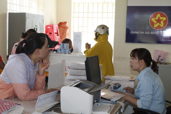 Một đại lý thu bảo hiểm tại xã Ea Siên tuyên truyền chính sách bảo hiểm cho người dân đến giao dịch tại Bưu điện văn hóa xã.