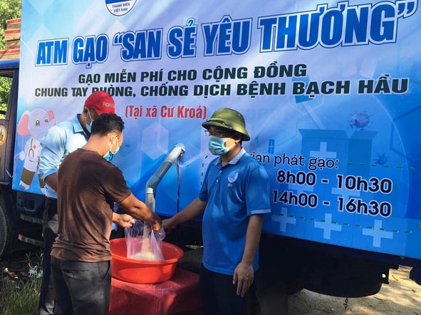 Thanh niên tình nguyện hỗ trợ người dân xã Cư Króa (huyện M'Đrắk) nhận gạo từ máy ATM.