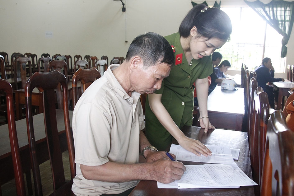 Chiến sĩ Đội Cảnh sát quản lý hành chính về trật tự xã hội (Công an TP. Buôn Ma Thuột) hướng dẫn người dân xã Ea Kao viết tờ khai thông tin cá nhân.   