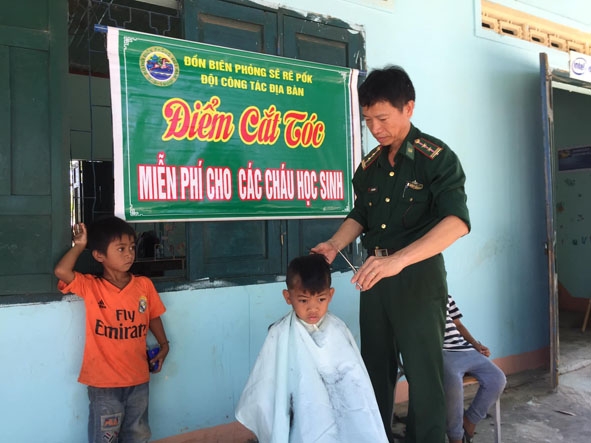 Trung tá quân nhân chuyên nghiệp Đỗ Văn Nhương, Đội phó vận động quần chúng Đồn Biên phòng Sêrêpốk cắt tóc cho học sinh. 