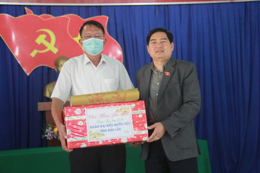 Phó Trưởng đoàn Chuyên trách Đoàn Đại biểu Quốc hội tỉnh Y Khút Niê tặng quà đại diện đảng ủy xã Cư San