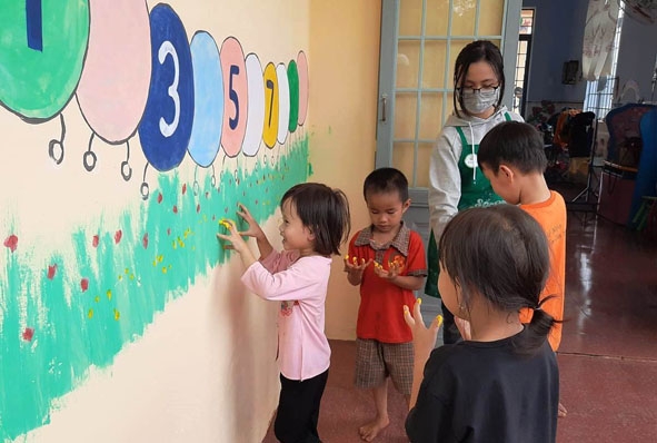 Các em học sinh hào hứng tham gia trải nghiệm vẽ sơn lên tường trường học tại điểm trường thôn Đoàn Kết (Trường Mẫu giáo Ea M'droh). 