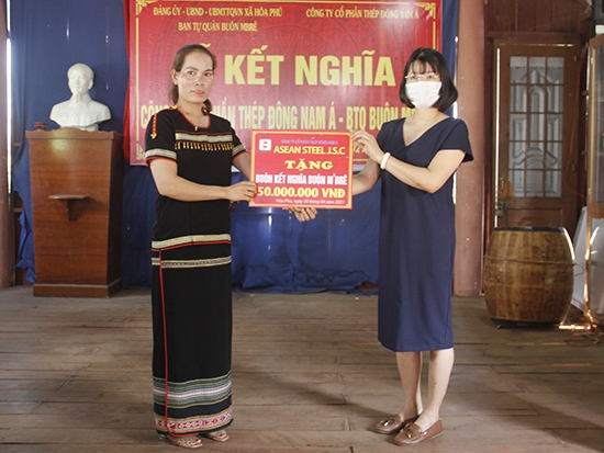 Bà Lê Thị Tuyết Hạ (bìa phải) Phó Tổng Giám đốc Công ty Cổ phần Thép Đông Nam Á trao tiền hỗ trợ tặng buôn kết nghĩa M'Brê 