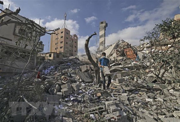 Người dân Palestine tìm kiếm đồ đạc còn sót lại trong toà nhà đã bị phá hủy bởi các cuộc không kích  của máy bay Israel xuống Dải Gaza.  Ảnh: AFP/TTXVN