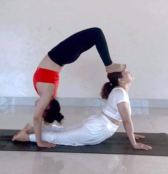 Chị Lê Thị Danh (bên phải) thực hiện một động tác trong yoga.