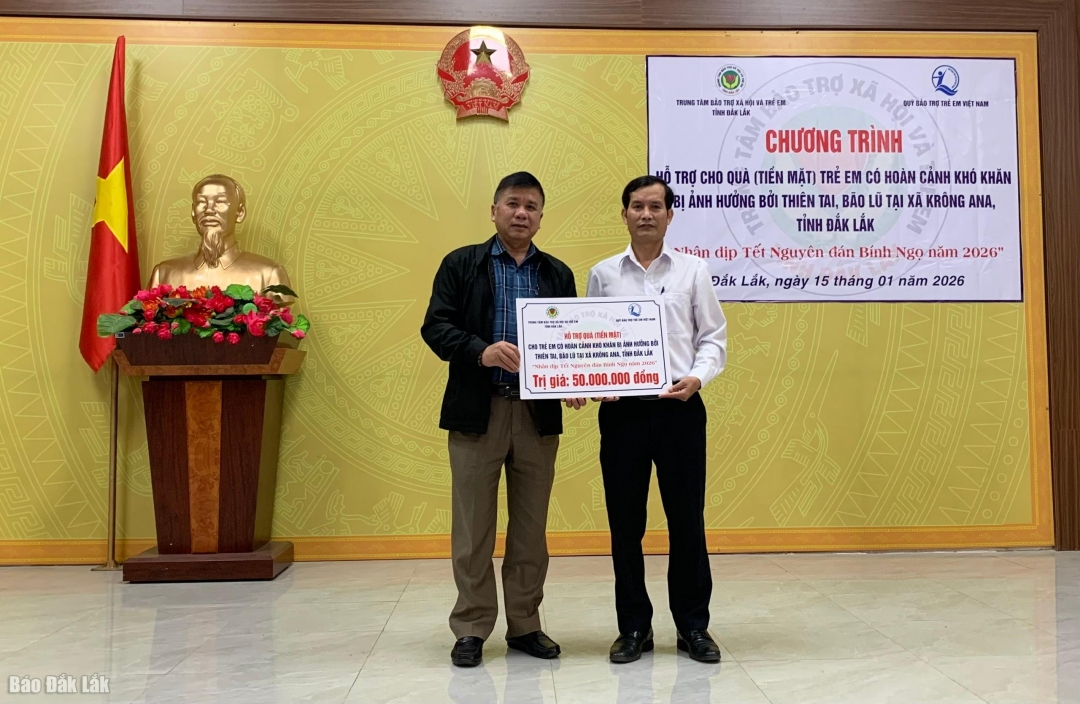 Phó Giám đốc Trung tâm bảo trợ xã hội và trẻ em Đắk Lắk (bìa trái) trao bảng tượng trưng tặng quà cho lãnh đạo Phòng Văn hóa Xã hội xã Krông Ana