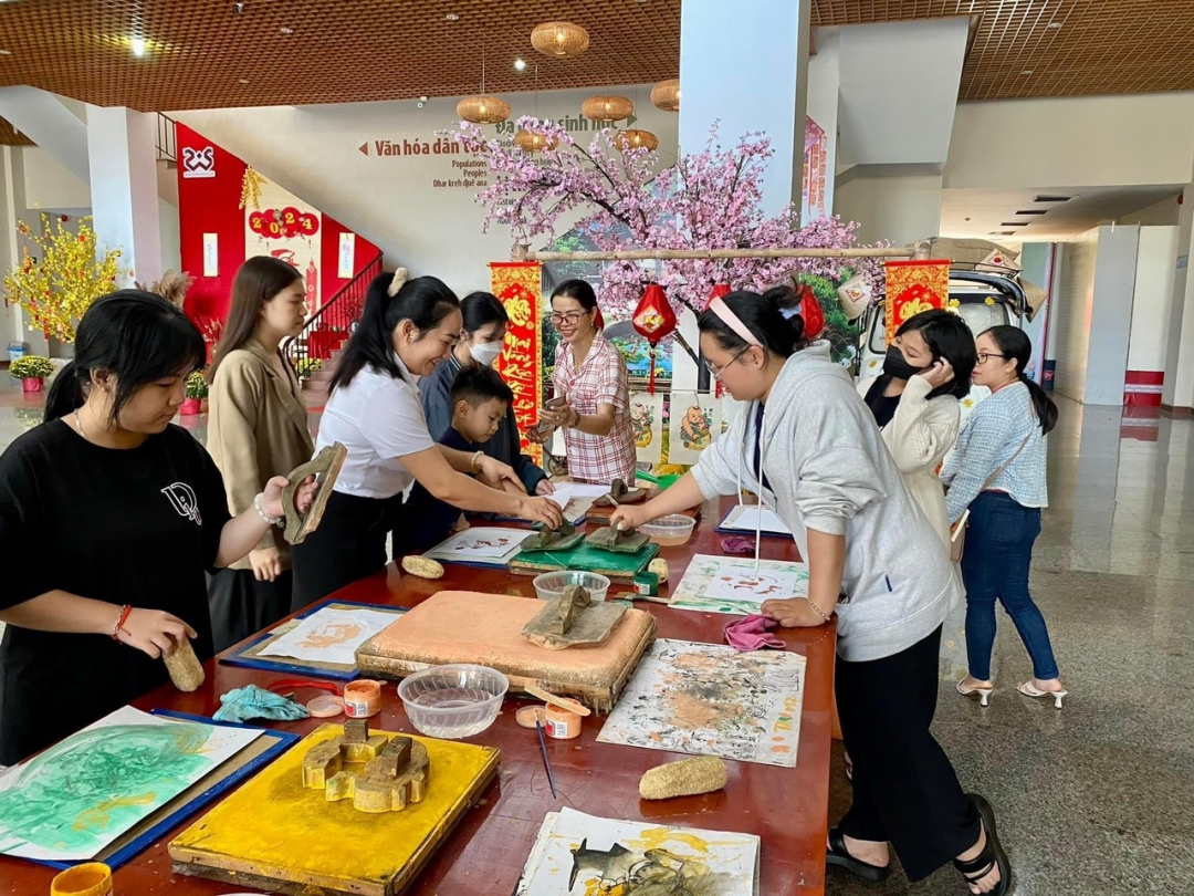 Du khách hào hứng tham gia hoạt động trải nghiệm chương trình in tranh dân gian bằng mộc bản tại Bảo tàng Đắk Lắk. 