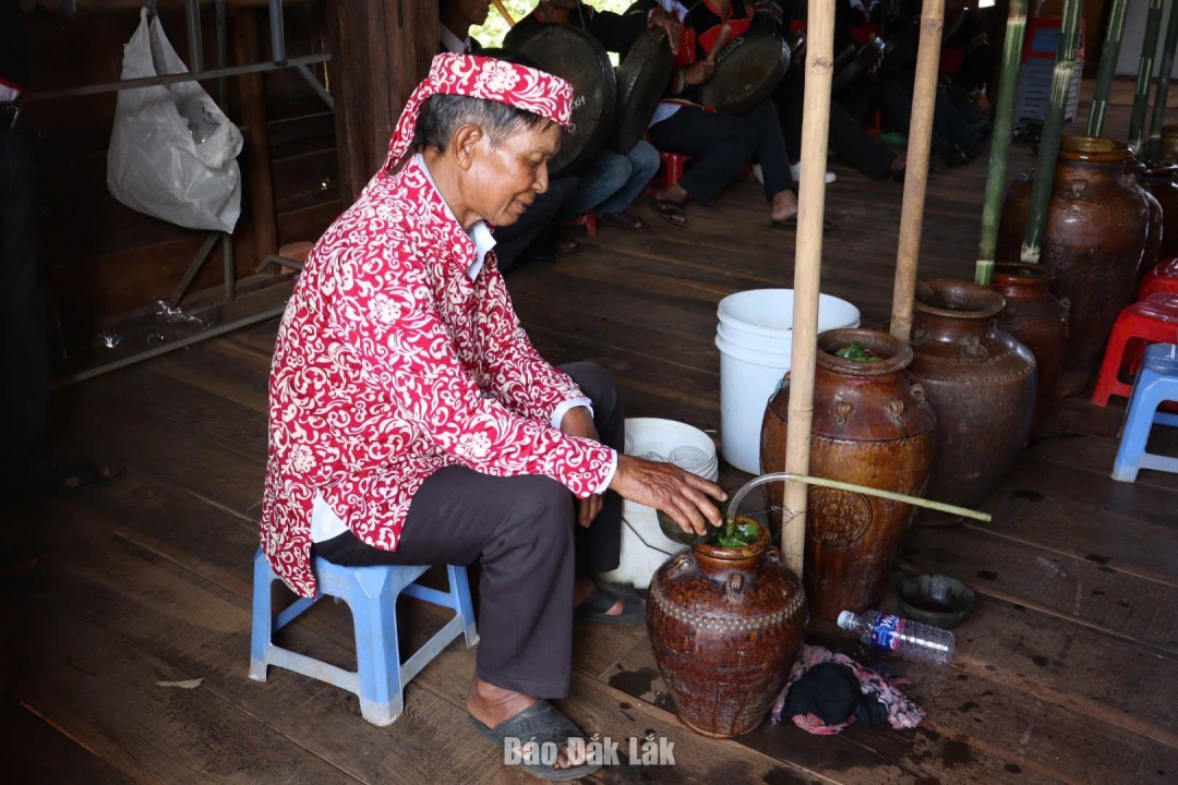 thầy cúng lấy từng bầu nước mát từ bến về đổ vào các bình rượu cần để mọi người trong buôn cùng thưởng thức những chóe rượu thơm nồng.