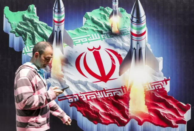 Một người dân đi ngang qua áp phích mô tả hình ảnh Iran phóng tên lửa, vào ngày 15/4/2024. Ảnh: Getty Images