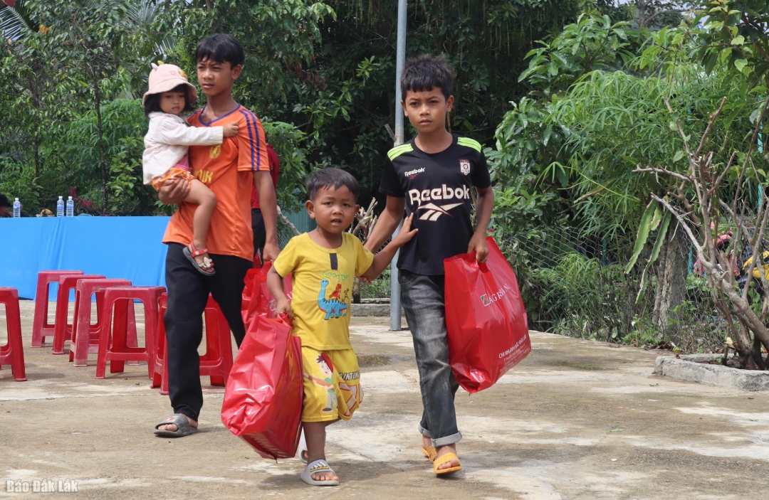 Các em thiếu nhi tại buôn Liêng Krắk phấn khởi mang những phần quà về nhà.