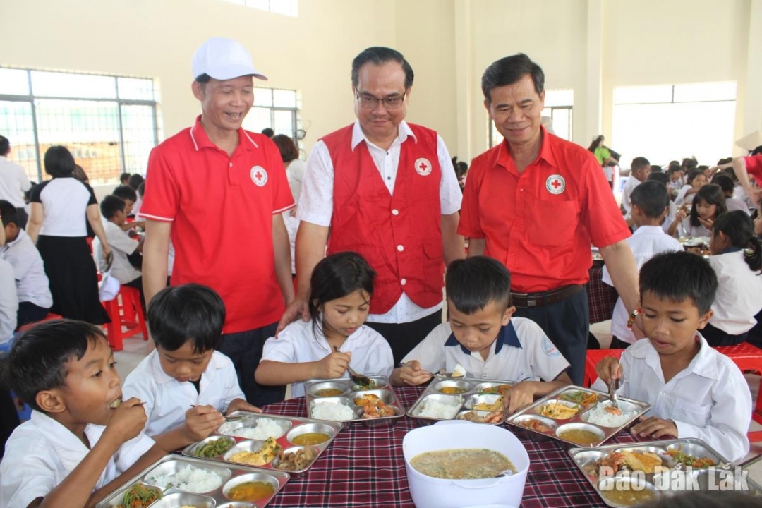 Phó Chủ tịch Trung ương Hội Chữ thập đỏ Việt Nam Vũ Thanh Lưu (giữa) cùng lãnh đạo Hội Chữ thập đỏ các tỉnh dự bữa ăn dinh dưỡng cho học sinh Trường Tiểu học Ea Hồ.