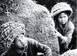 rẻ em đội mũ rơm ẩn nấp dưới giao thông hào tránh bom Mỹ. (Ảnh: TL)
