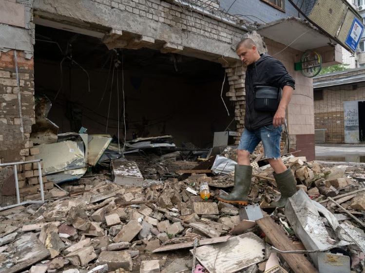 Một cư dân Ukraine dọn dẹp đống đổ nát do xung đột gây ra. Ảnh: AFP