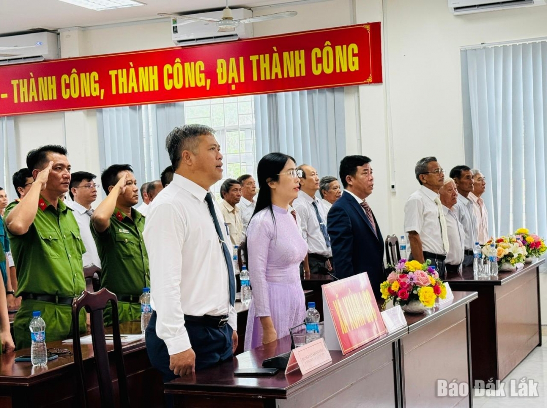 Các đại biểu thực hiện nghi thức chào cờ tại Lễ công bố các nghị quyết, quyết định của Trung ương và địa phương về sáp nhập đơn vị hành chính tỉnh Đắk Lắk, tại điểm cầu xã Xuân Lộc.