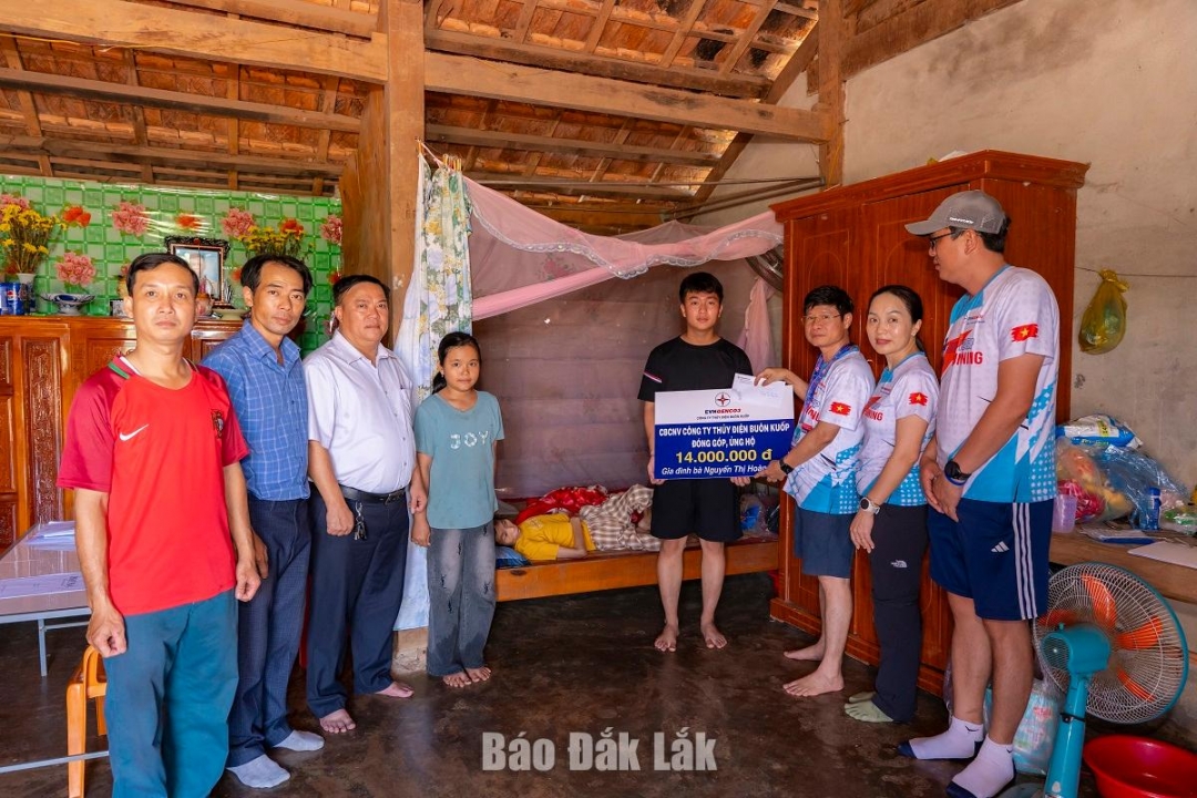 Đại diện Công ty Thủy điện Buôn Ku ốp trao hỗ trợ cho mẹ con chị Lan