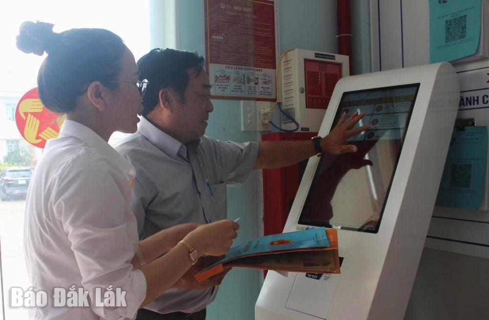 Cán bộ công chức xã Hòa Phú hướng dẫn người dân bấm số thứ tự thực hiện thủ tục hành chính. Ảnh minh họa