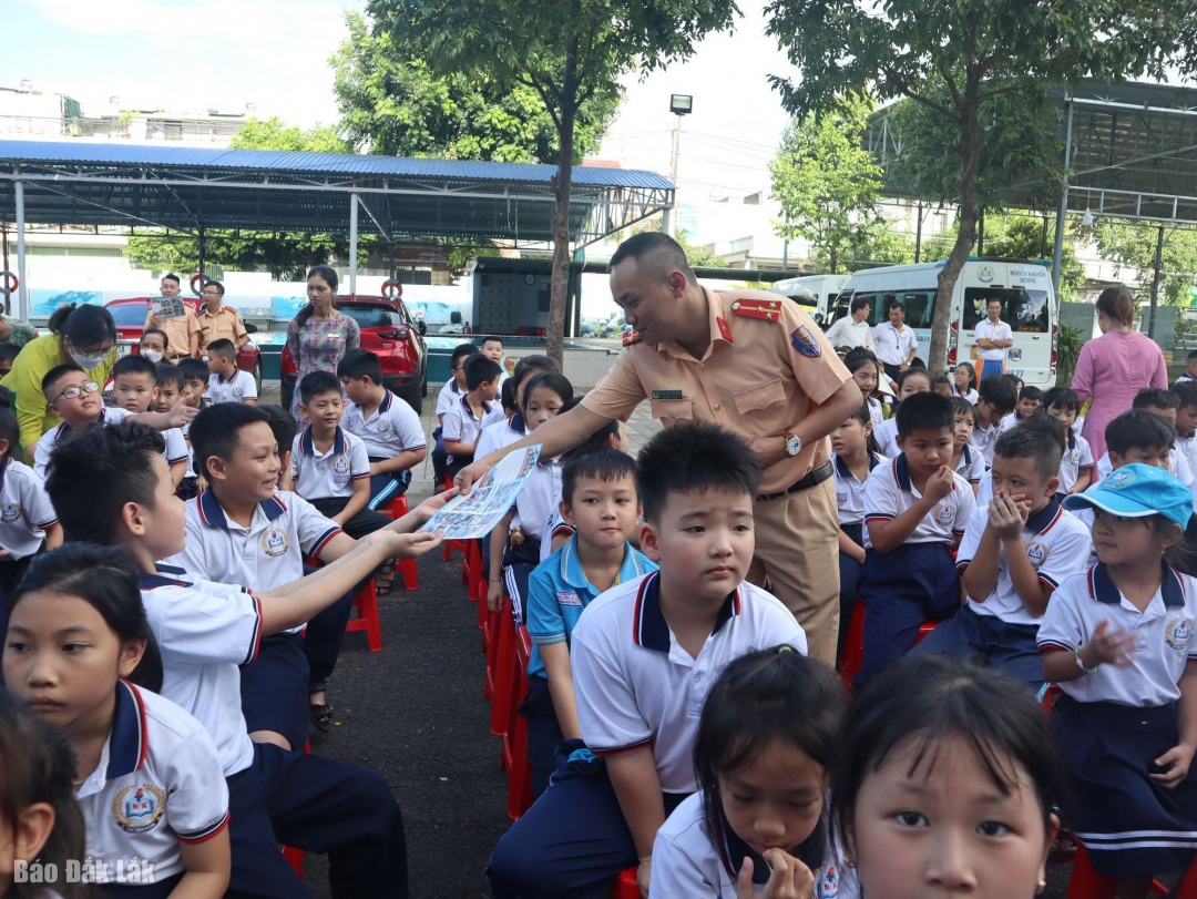 Cán bộ Đội Cảnh sát giao thông - Trật tự (Công an TP. Buôn Ma Thuột) tuyên truyền, phát tờ rơi về an toàn giao thông cho học sinh.