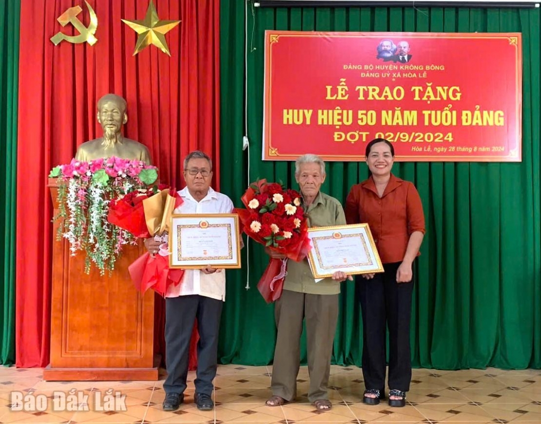 Phó Bí thư Thường trực Huyện ủy Kr ông Bông HKim Rơ Chăm trao Huy hiệu đảng tặng