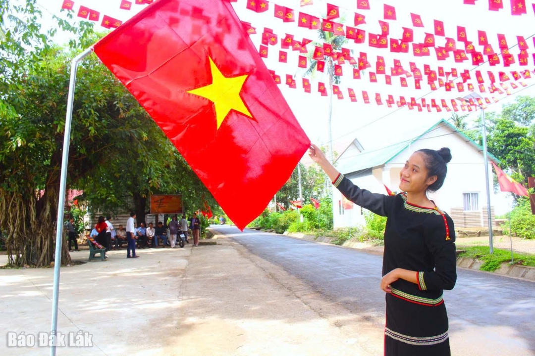 Một thiếu nữ Ê Đê bên công trình Tự hào cờ Tổ quốc năm 2025 của UBND xã Hòa Phú.