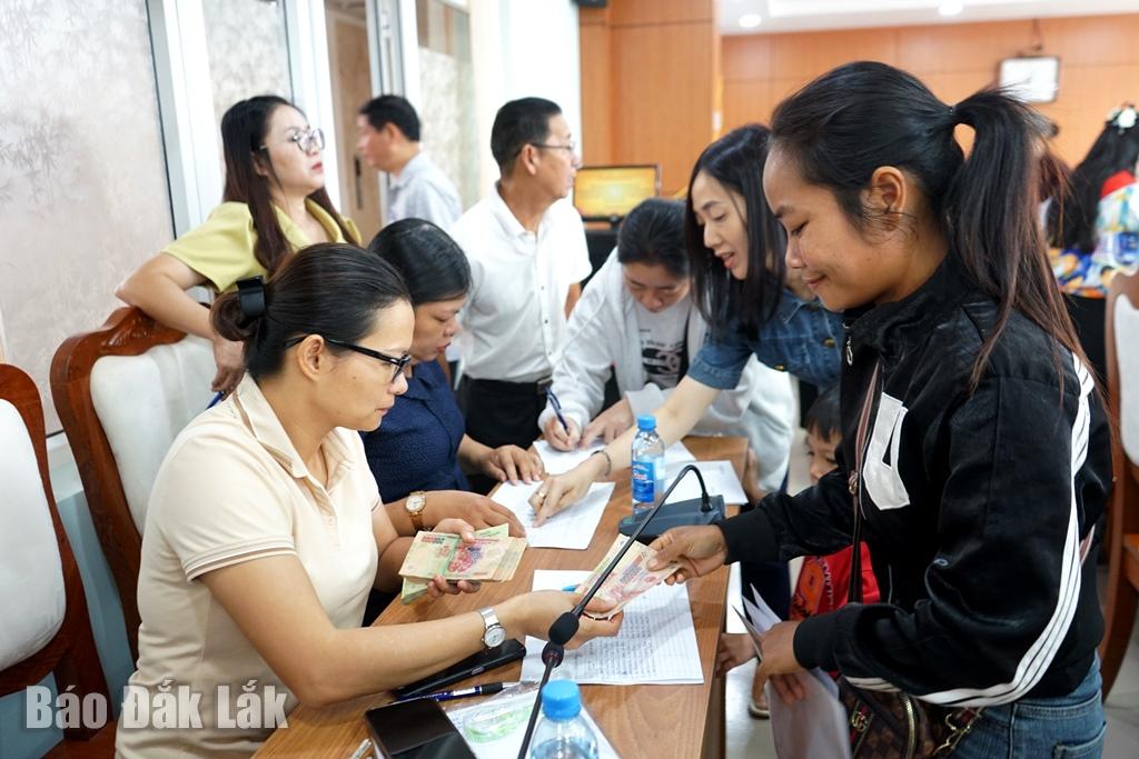 Chị H Yol Êban, buôn Ea Bông, phường Buôn Ma Thuột (bìa phải) đại diện nhận tiền cho các thành viên trong gia đình