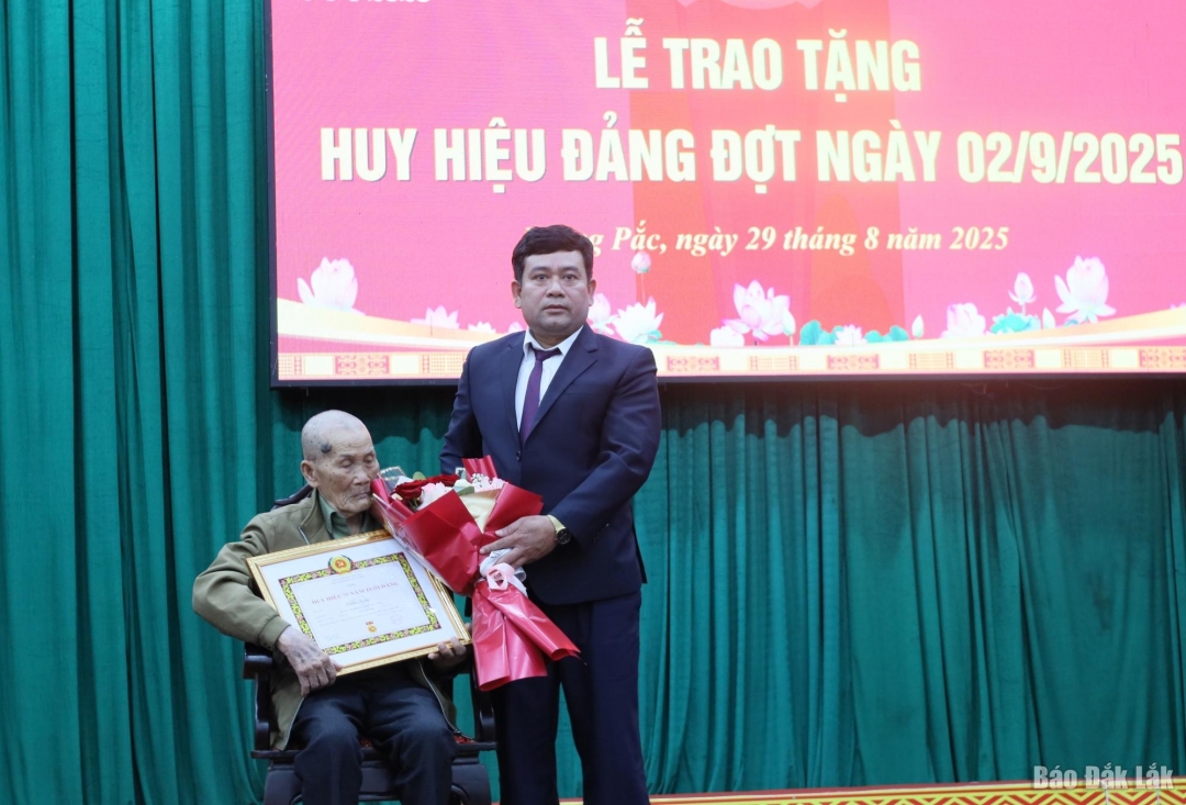 Phó Bí thư Thường trực Đảng ủy xã Y Djoang Niê trao Huy hiệu Đảng cho đảng viên Trần Ngãi có 75 năm tuổi đảng.