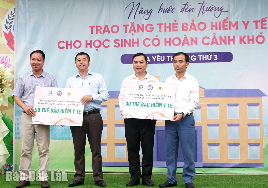 Đại diện Báo Dân trí và Sở Lao động - Thương binh và Xã hội trao bảng tượng trưng tặng thẻ bảo hiểm y tế cho Phòng Giáo dục TP. Buôn Ma Thuột và huyện Ea Hleo