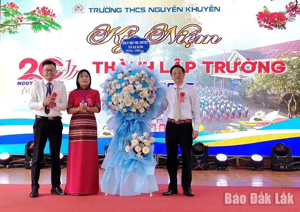 Phó Chủ tịch UBND xã Ea Kar Nguyễn Thanh Dương (bìa trái) tặng lẵng hoa của Đảng ủy - HĐND - UBND - Ủy ban MTTQ Việt Nam xã chúc mừng Trường THCS Nguyễn Khuyến.