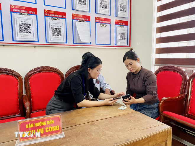 Lãnh đạo Trung tâm phục vụ hành chính công xã Kỳ Thượng (tỉnh Hà Tĩnh) trực tiếp hướng dẫn người dân đăng ký hồ sơ trực tuyến. Ảnh: Hữu Quyết/TTXVN