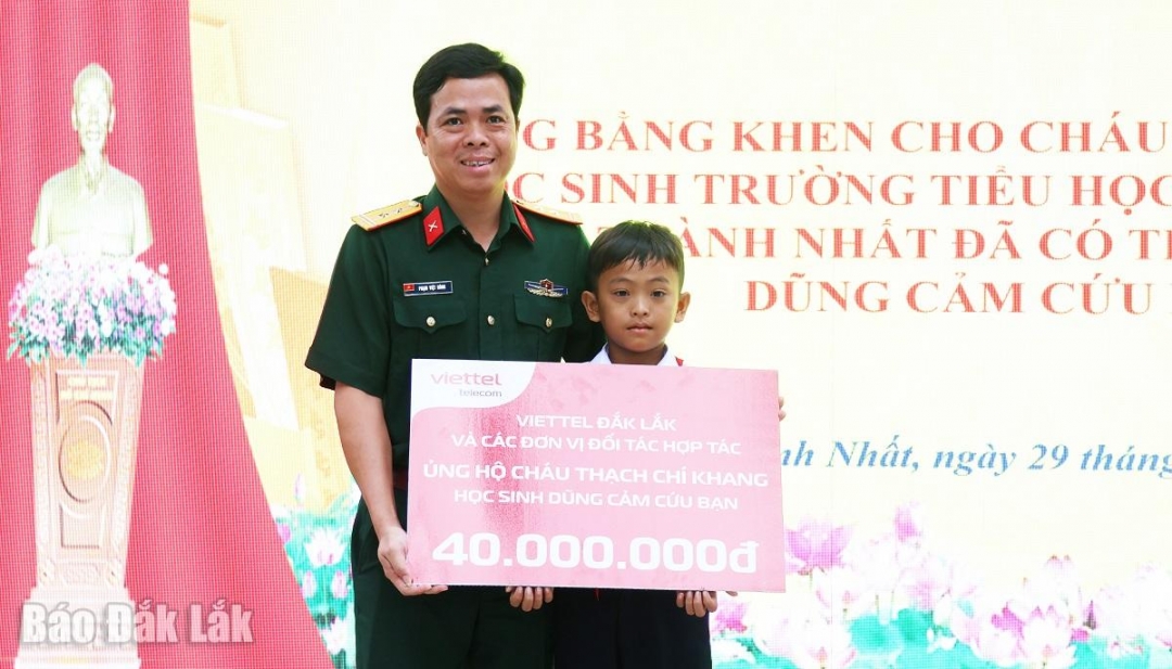 Trung tá Phạm Việt Hùng, Giám đốc Viettel Đắk Lắk trao biển tượng trưng hỗ trợ 40 triệu đồng cho em Thạch Chí Khang để làm sổ tiết kiệm, trang trải chi phí học tập.