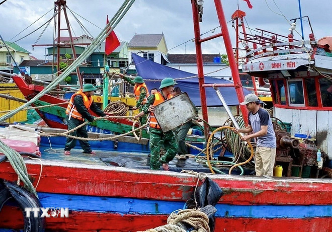 Cán bộ, chiến sỹ Đồn Biên phòng Diễn Thành (Bộ đội Biên phòng tỉnh Nghệ An) triển khai lực lượng hỗ trợ ngư dân đưa tàu thuyền vào nơi tránh trú bão, neo đậu, chằng néo phương tiện, thu dọn ngư lưới cụ. Ảnh: TTXVN