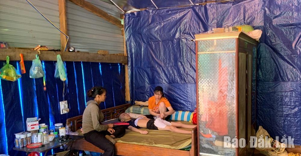 Chị Nông Thị Vân chăm sóc con trai trong căn nhà gỗ tạm bợ. 