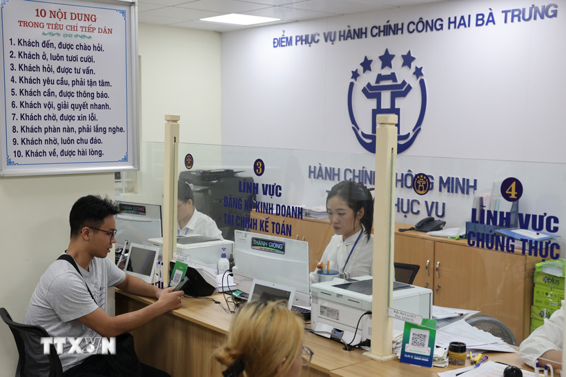 Người dân được cán bộ, công chức hỗ trợ giải quyết hồ sơ tại Điểm phục vụ Hành chính công phường Hai Bà Trưng (Hà Nội). Ảnh: TTXVN