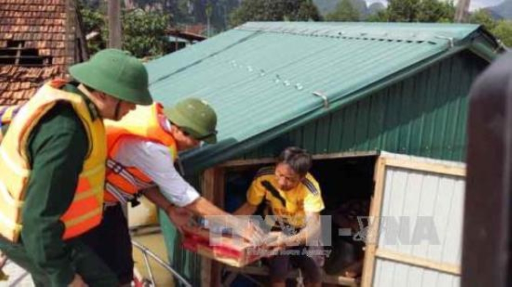 Lãnh đạo địa phương cùng lực lượng biên phòng trên địa bàn tỉnh Quảng Bình thăm hỏi và trao hàng cứu trợ cho bà con vùng lũ huyện Minh Hóa. (Ảnh: TTXVN)