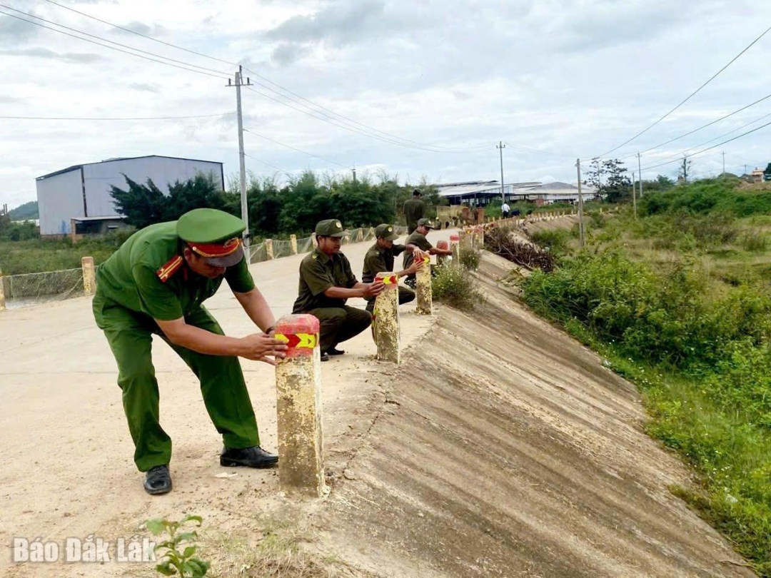 Cán bộ, chiến sĩ công an xã Tân Tiến và lực lượng an ninh cơ sở dán decal phản quang các cọc tiêu khu vực có nguy cơ mất an toàn giao thông.