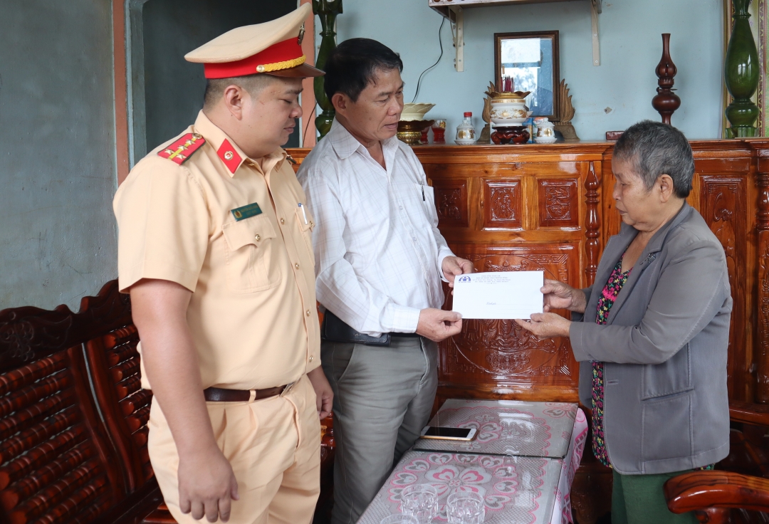 Chánh Văn phòng Ban An toàn giao thông tỉnh Bùi Văn Ngọc (áo trắng) trao tiền hỗ trợ cho thân nhân người tử vong do tai nạn giao thông tại buôn Êcăm, thị trấn Buôn Trấp.