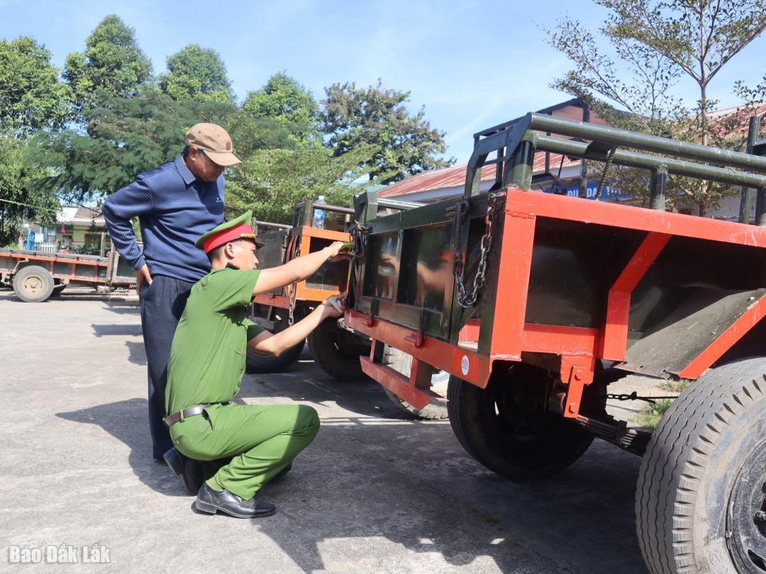 Cán bộ Công an xã Yang Tao, huyện Lắk dán decal phản quang cho xe máy cày.