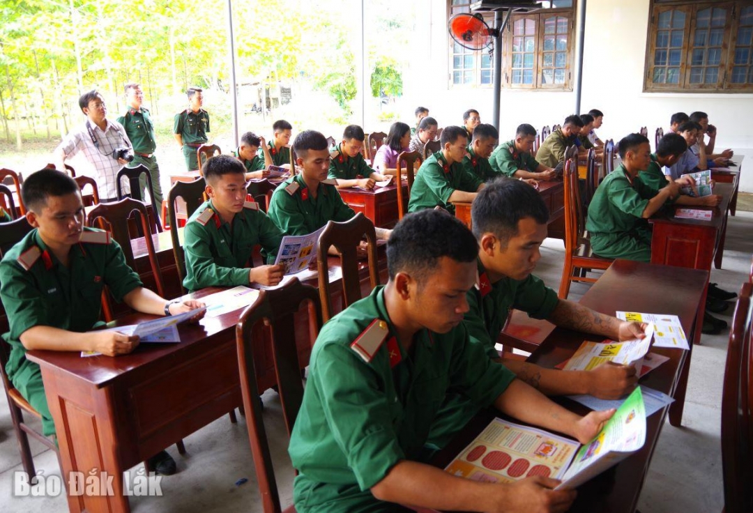 Cán bộ, chiến sĩ lực lượng vũ trang và người dân trên địa bàn theo dõi thông tin tuyên truyền qua tờ rơi tuyên truyền.