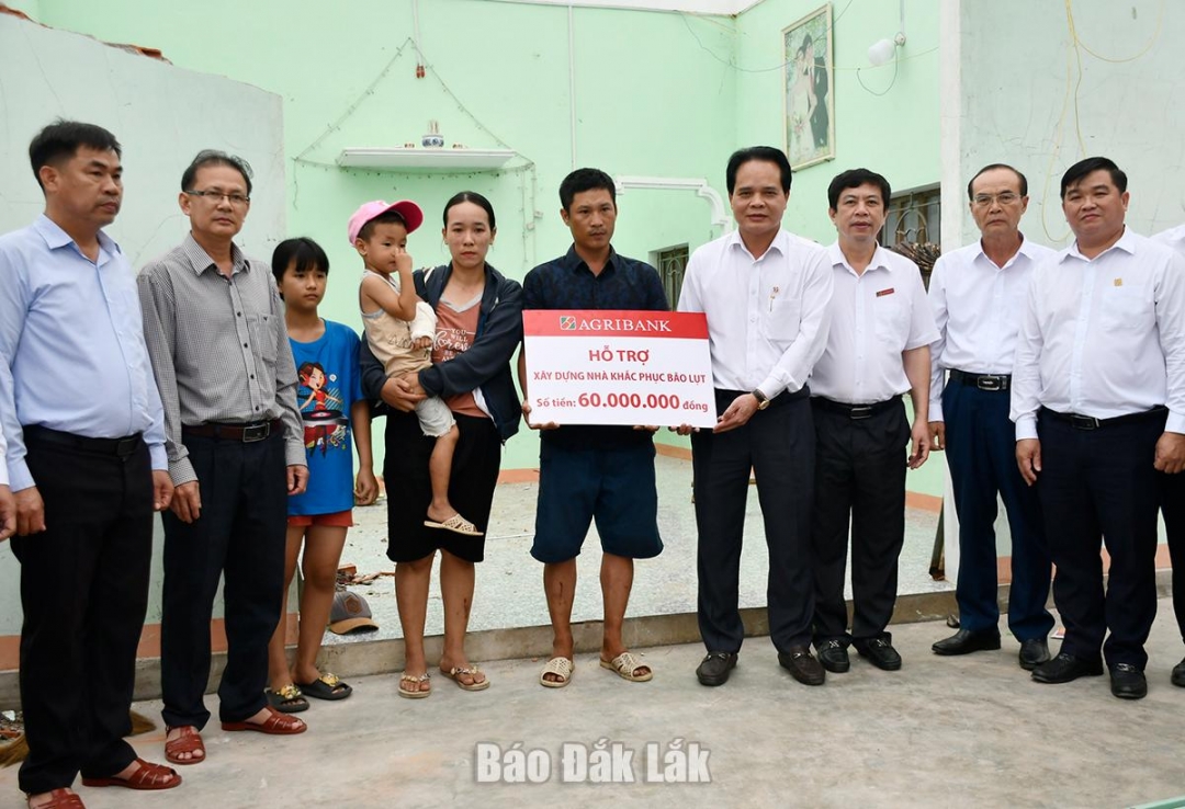 Phó Tổng Giám đốc Agribank Vương Hồng Lĩnh trao bảng tượng trưng hỗ trợ 60 triệu đồng cho gia đình anh Nguyễn Văn Khoa ở thôn Thọ Lộc, xã Xuân Lộc.