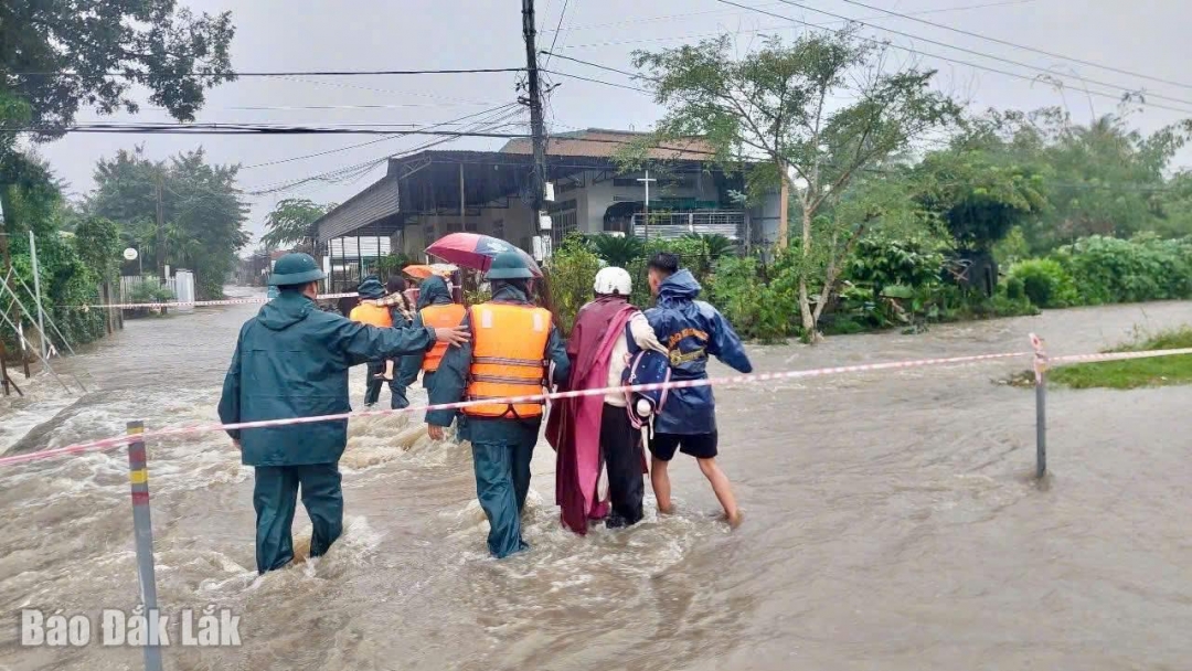 Lực lượng chức năng xã Ea Phê hỗ trợ người dân di chuyển qua khu vực ngập lụt.