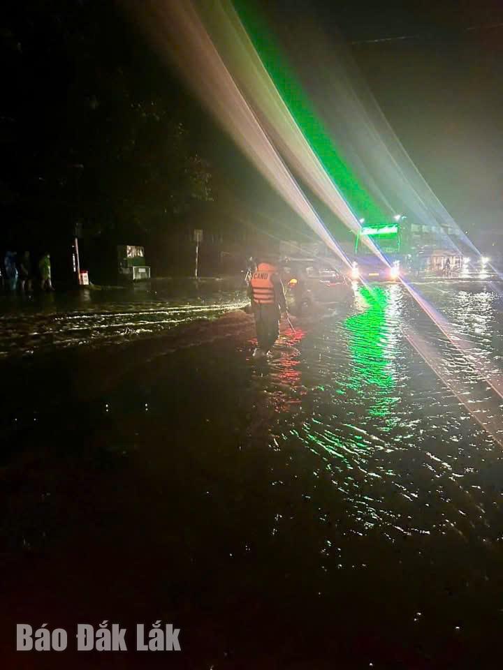 Lực lượng công an hướng dẫn lưu thông tại một điểm ngập lụt trên Quốc lộ 26 qua địa bàn xã Ea Phê tối 19/11.