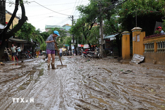 Người dân dọn bùn trên tuyến đường Nguyễn Tri Phương, khối Kiên Trung, phường Hội An. Ảnh: TTXVN
