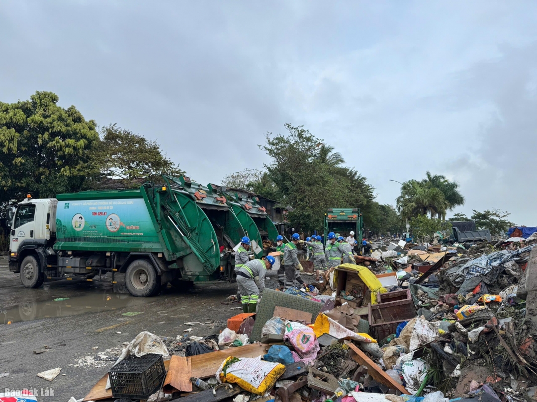 Xe máy cùng công nhân của Công ty Cổ phần Môi trường đô thị Quảng Ngãi tham gia thu gom rác thải sau lũ trên đường Bạch Đằng.