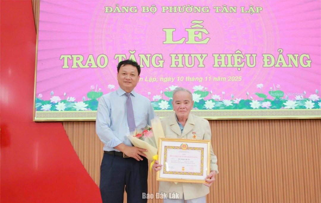 Bí thư Đảng ủy, Chủ tịch HĐND phường Tân Lập Vũ Văn Hưng trao Huy hiệu 65 năm tuổi Đảng cho đảng viên.