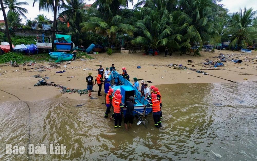 Lực lượng chức năng hỗ trợ người dân xã Tuy An Nam đưa tàu cá từ biển vào bờ để tránh bão.