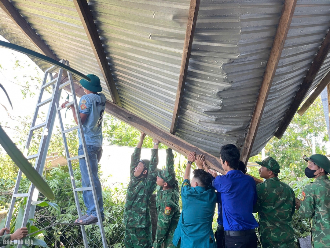 Các lực lượng dân quân, quân sự... hỗ trợ sửa chữa mái tôn ở nhà dân.