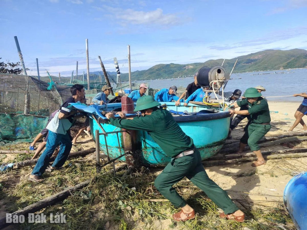 Cán bộ, chiến sĩ Đồn Biên phòng Xuân Hòa phối hợp địa phương giúp người dân thôn 2, xã Xuân Lộc đưa thúng chai trôi dạt do bão vào bờ.