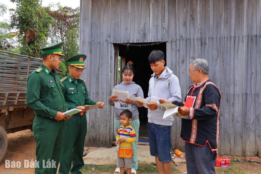 Già làng Y Thơng Kđoh cùng bộ đội biên phòng phát tờ rơi, tuyên truyền pháp luật để người dân nắm bắt.