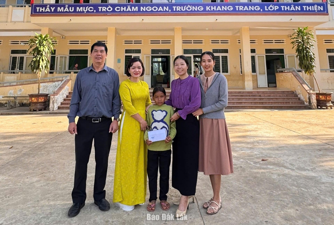 Đại diện cán bộ Phòng Văn hóa - Xã hội xã Đắk Phơi và Ban giám hiệu Trường Tiểu học Lê Thị Hồng Gấm trao tiền hỗ trợ cho em H Thêm Liêng Hót.