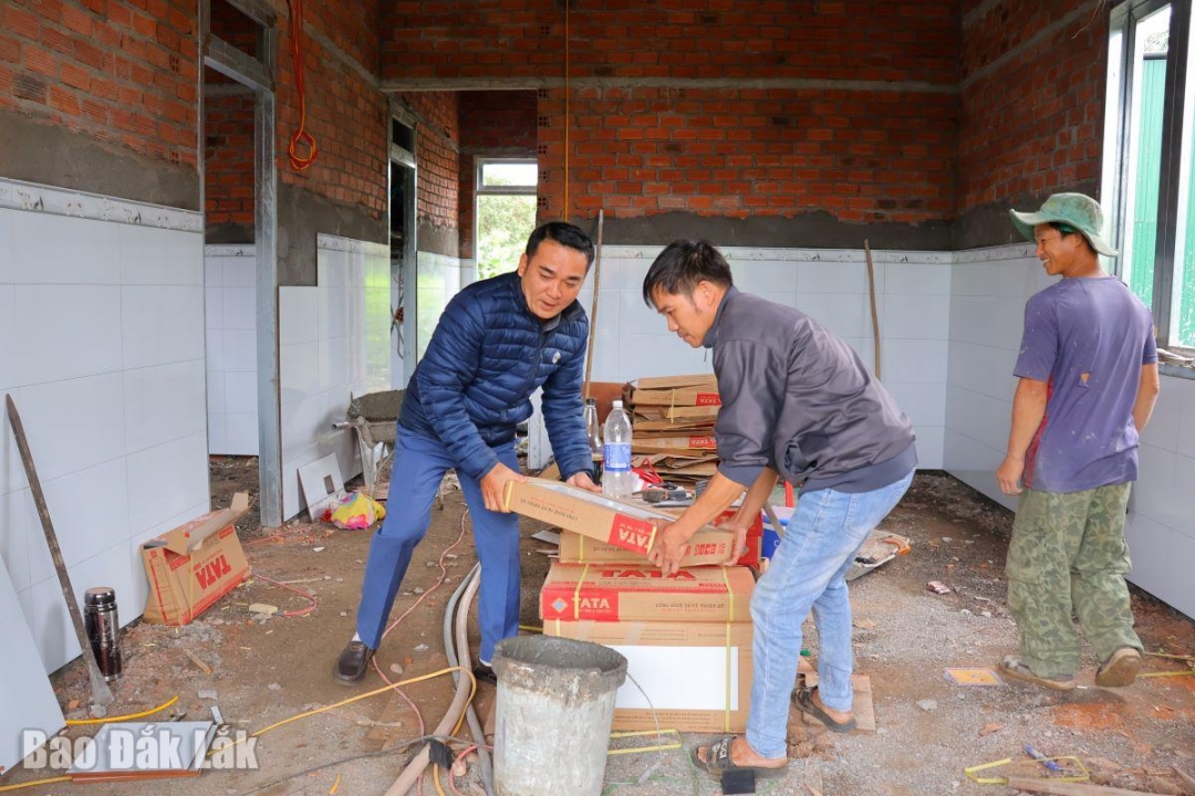 Cán bộ Phòng Văn hóa - Xã hội xã Ea Nuôl (bìa trái) xuống thăm, hỗ trợ người dân 